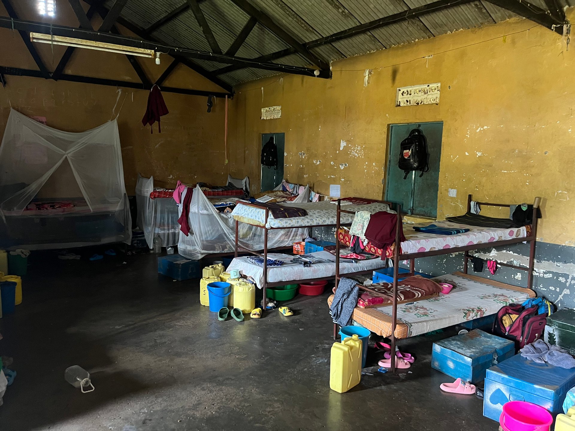 Boys dormitory at a boarding school near Butiru with metal bunk beds, mosquito nets and personal belongings in boxes