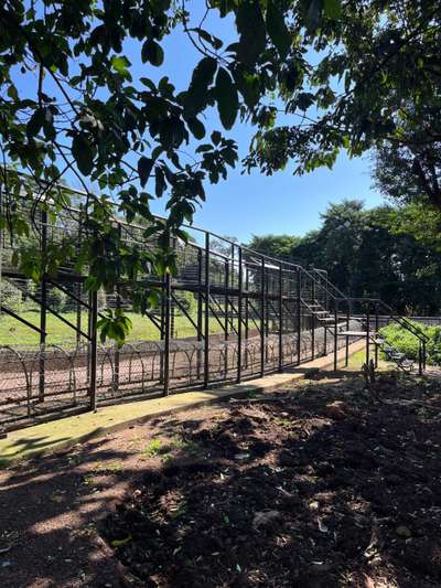 Metal enclosure fence at Ngamba Island Chimpanzee Sanctuary with forested rehabilitation area behind