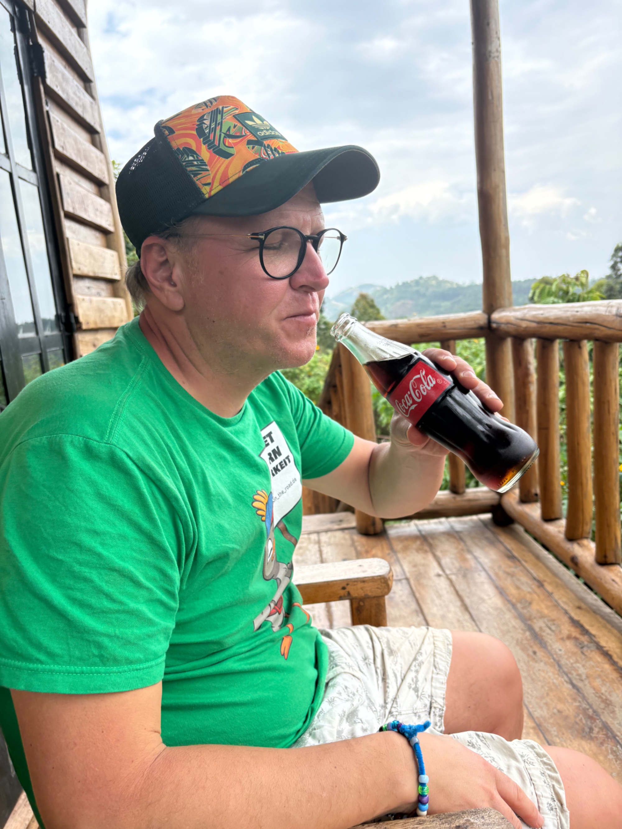 A man takes a break with a Coca-Cola on a wooden veranda in Buhoma, Uganda