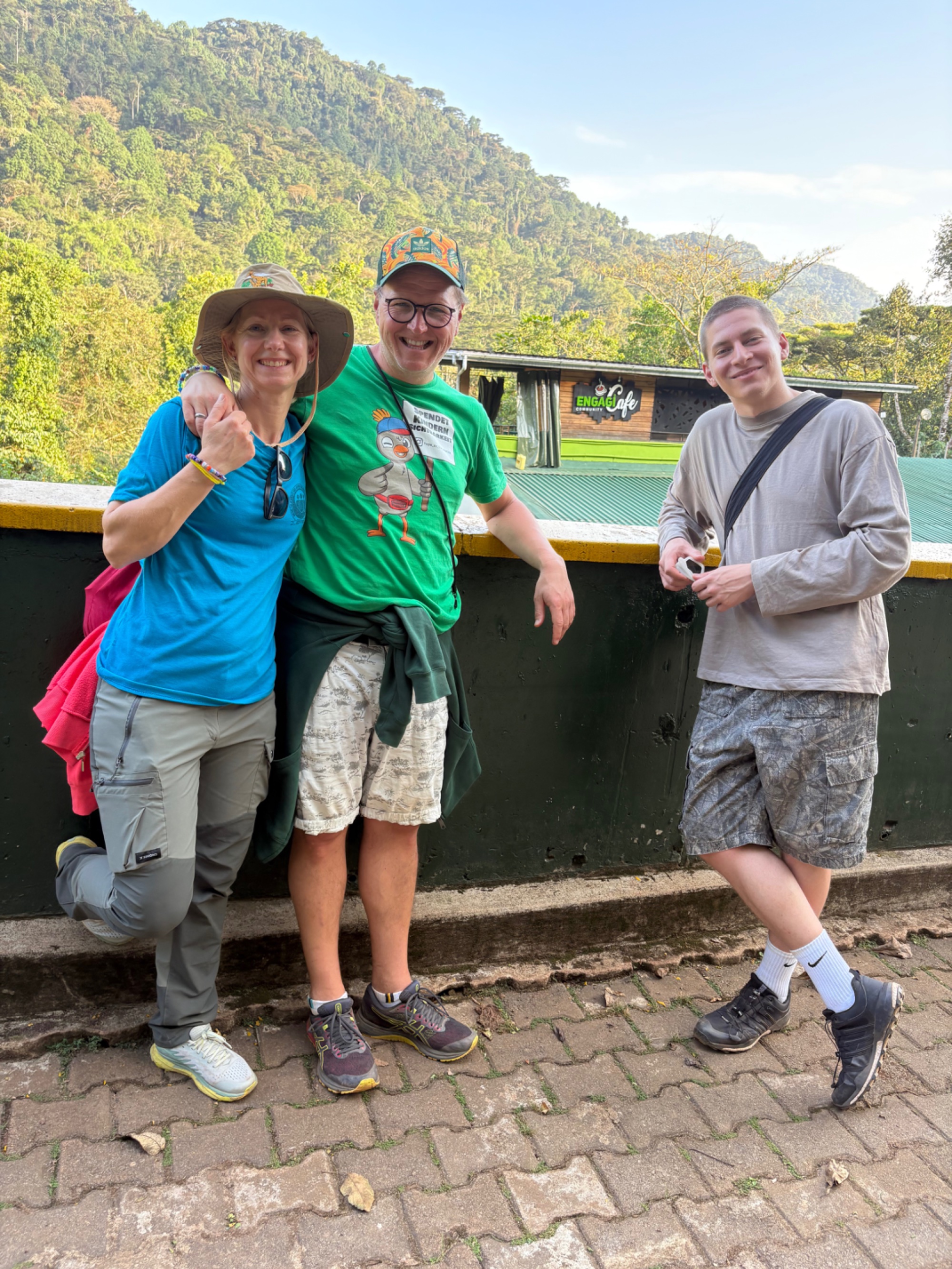Three people standing together laughing in front of a wall in Buhoma, Uganda