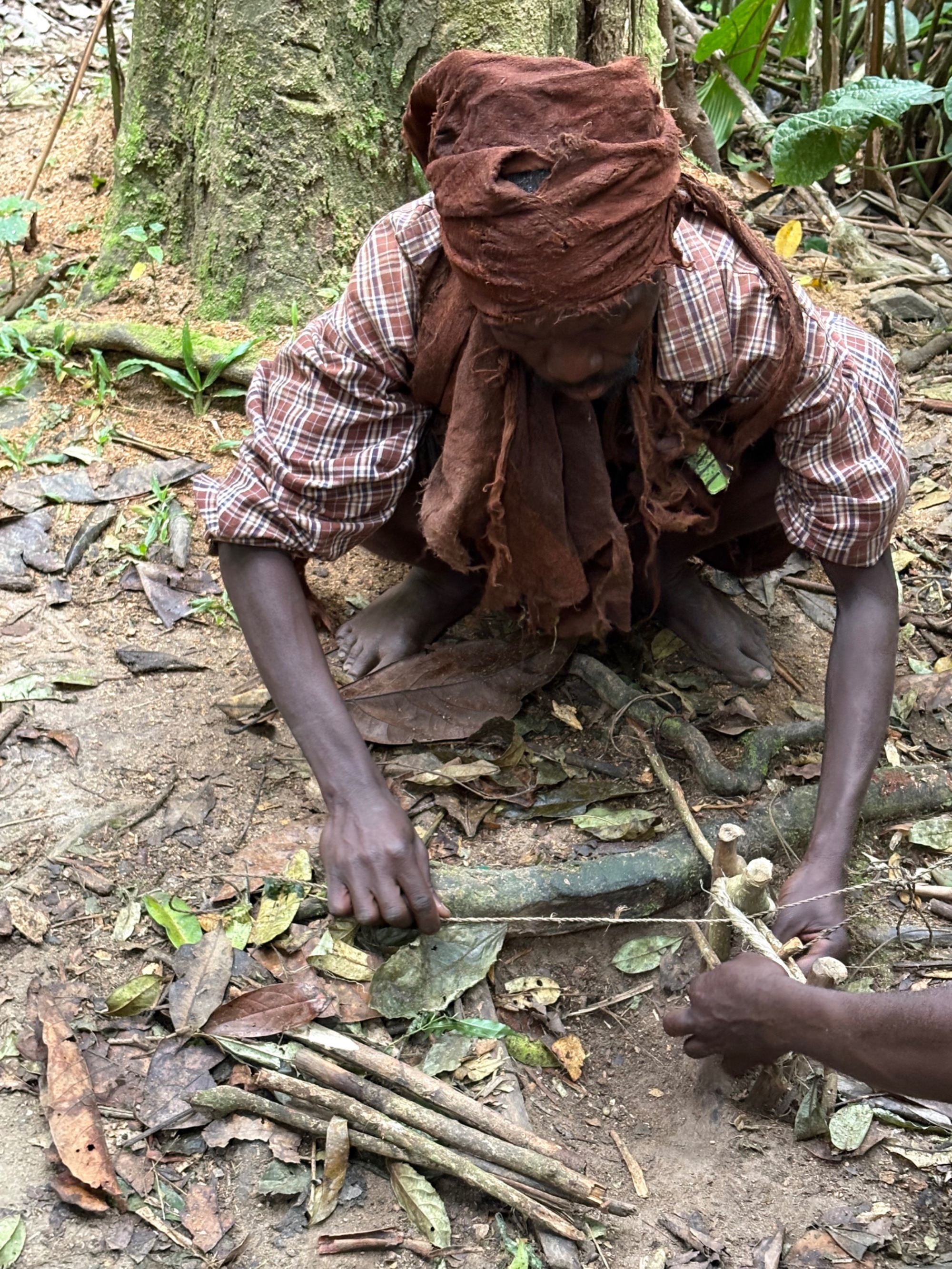 A Batwa man demonstrates a traditional hunting trap made from forest materials