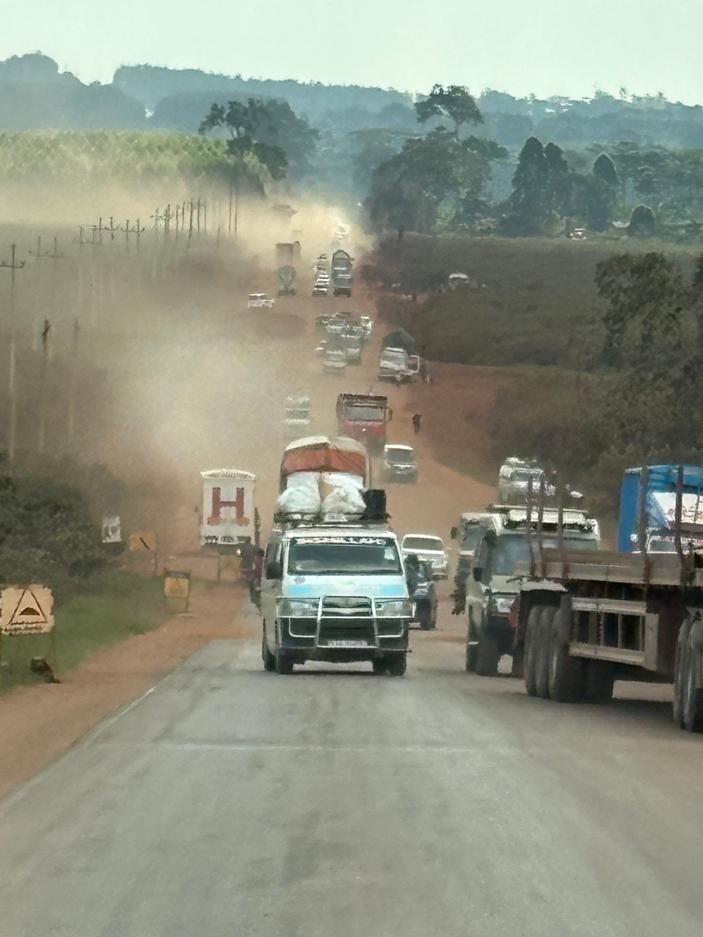 Masaka Highway under construction — minibuses, lorries and BodaBoda motorcycles navigate a dusty red-earth road