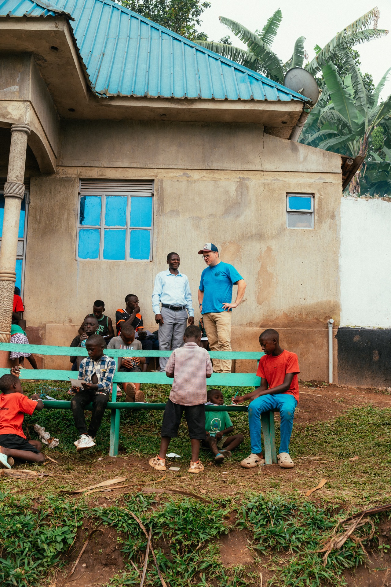 Mark with a local partner in front of the completed HopeKitchen with blue roof