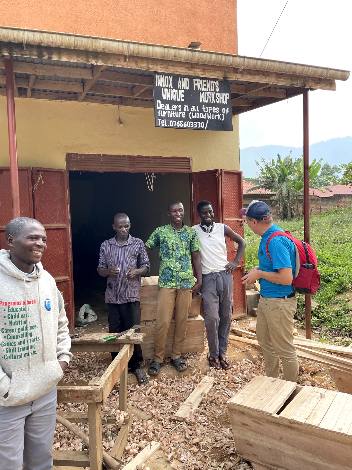 Four craftsmen and a visitor at the Innox and Friend's woodworking workshop in Buhoma, Uganda