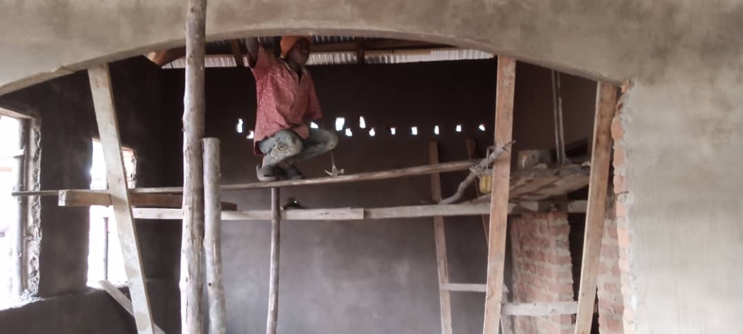Worker in an orange cap plastering the arched interior of HopeKitchen from a wooden scaffold