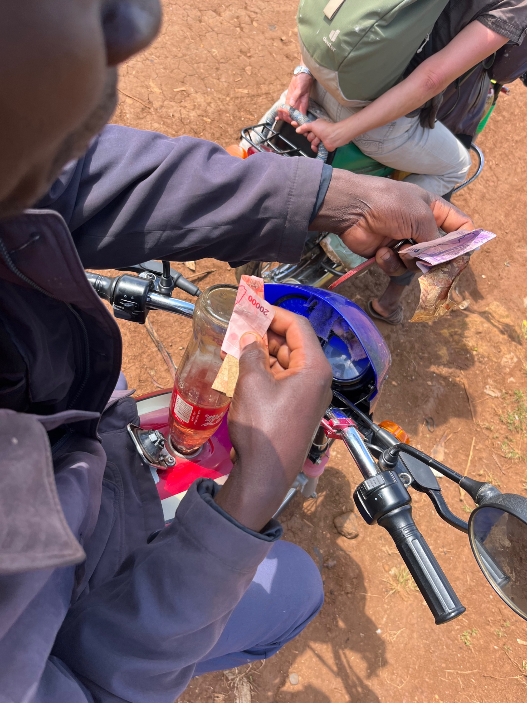 BodaBoda driver paying for petrol from a recycled cola bottle at a roadside fuel stop in Uganda