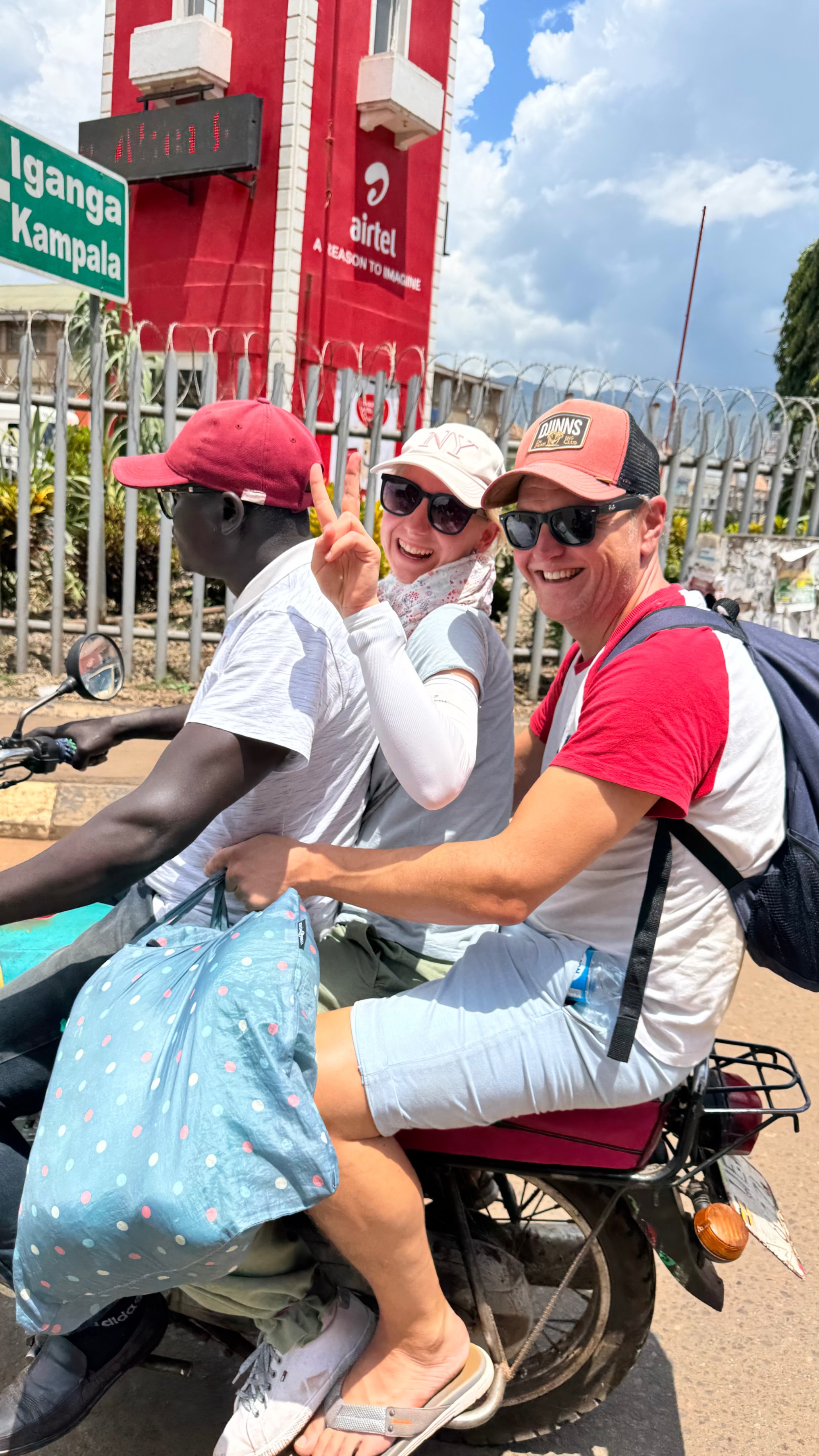 Mark and Susanne riding a BodaBoda motorcycle taxi through Jinja, Uganda, with their driver