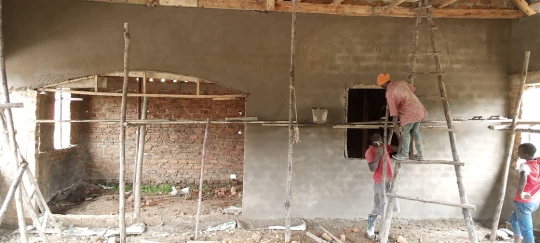 Workers plastering interior walls of HopeKitchen on wooden scaffolding