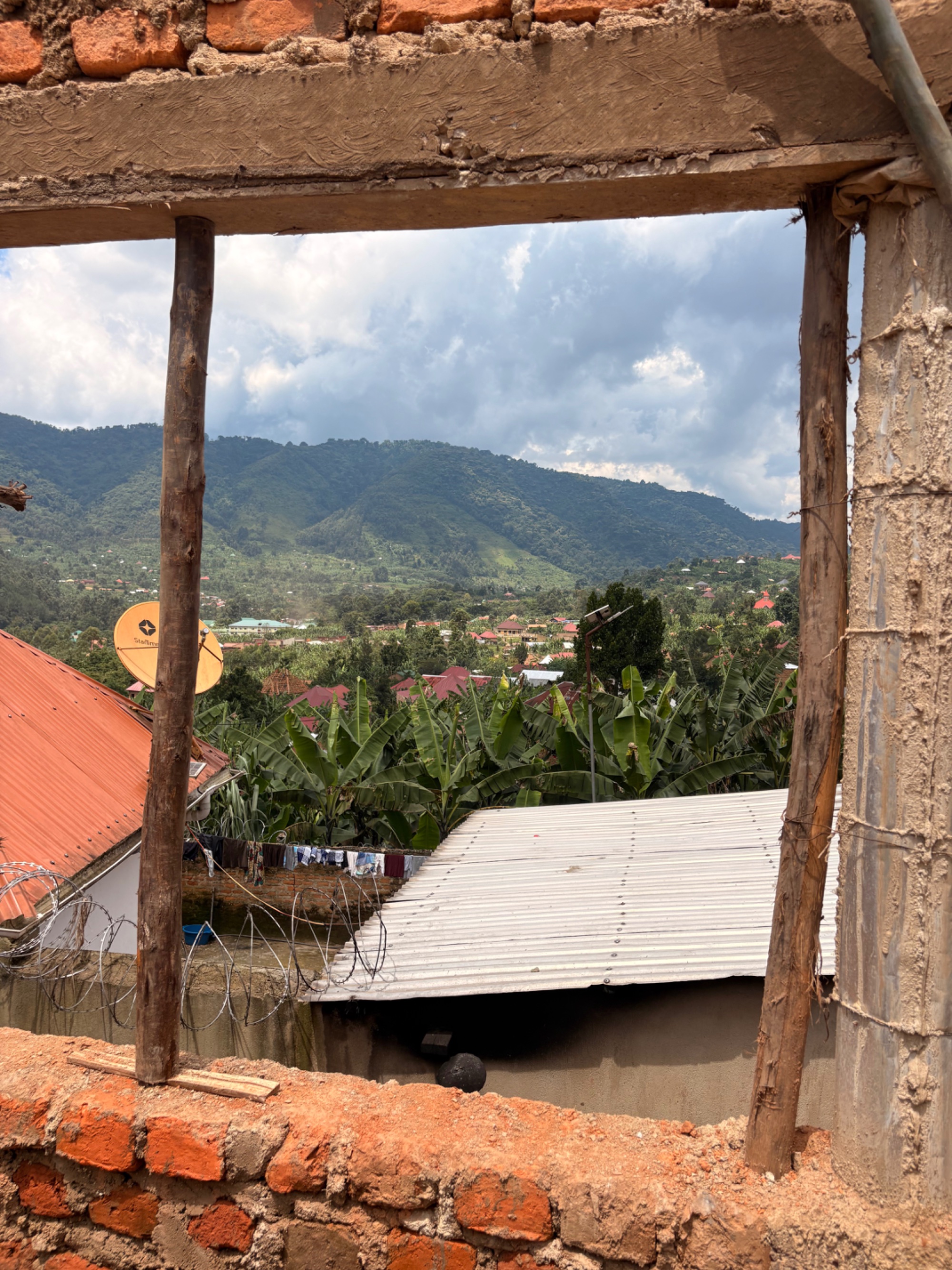 View through the unfinished window of HopeKitchen across the Buhoma valley with banana trees and mountains